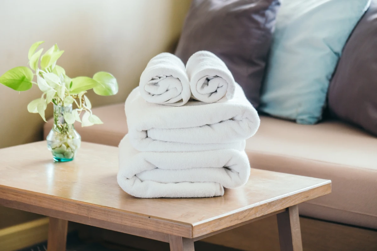 Stack of clean folded white towels on table in cosy living space